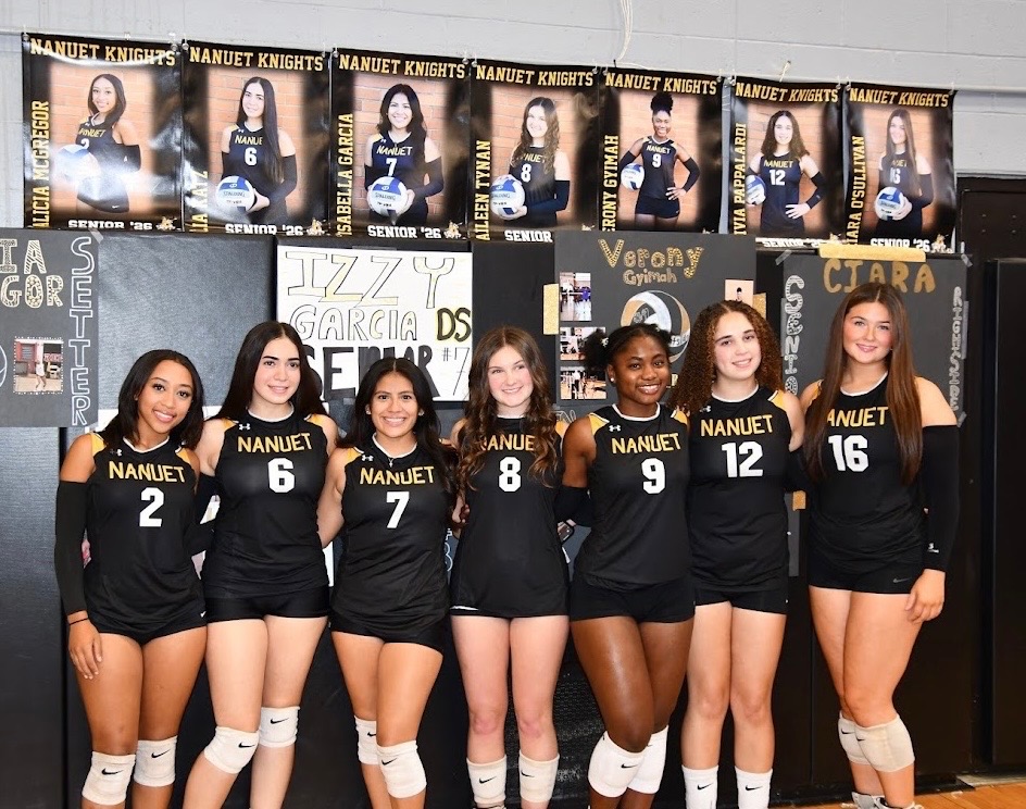 Seniors on Nanuet's Varsity Volleyball Team pose underneath their posters for a picture together. 